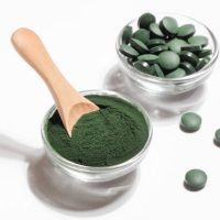 natural additives and superfood. green spirulina algae powder and pills in glass bowls on white background. healthy lifestyle concept. organic food